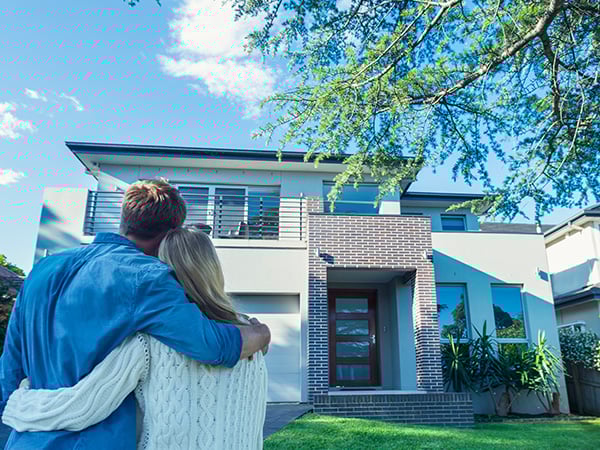 Happy couple holding each other looking at their house